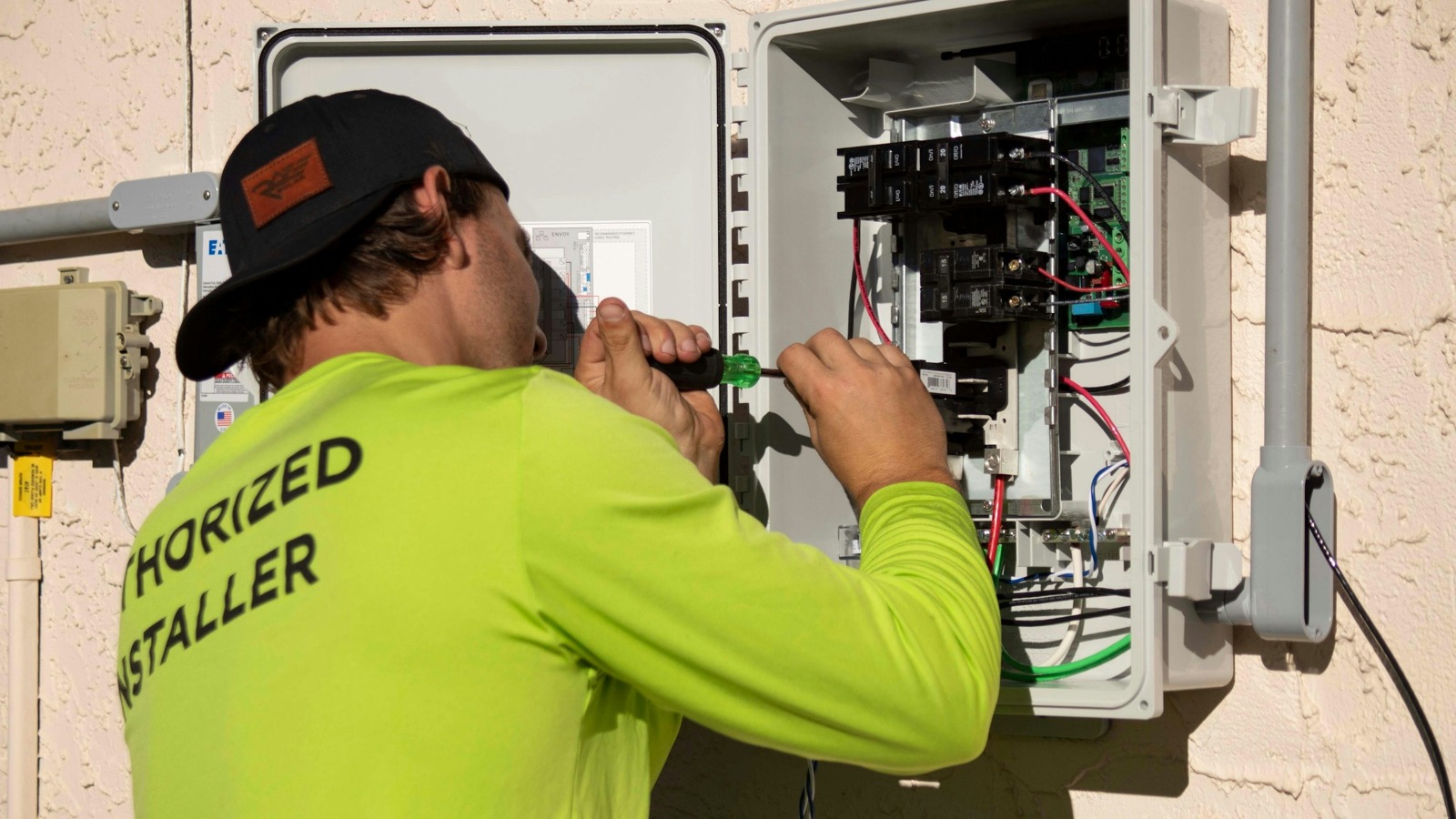 HVAC technician working on an outdoor air conditioning unit in bright sunlight