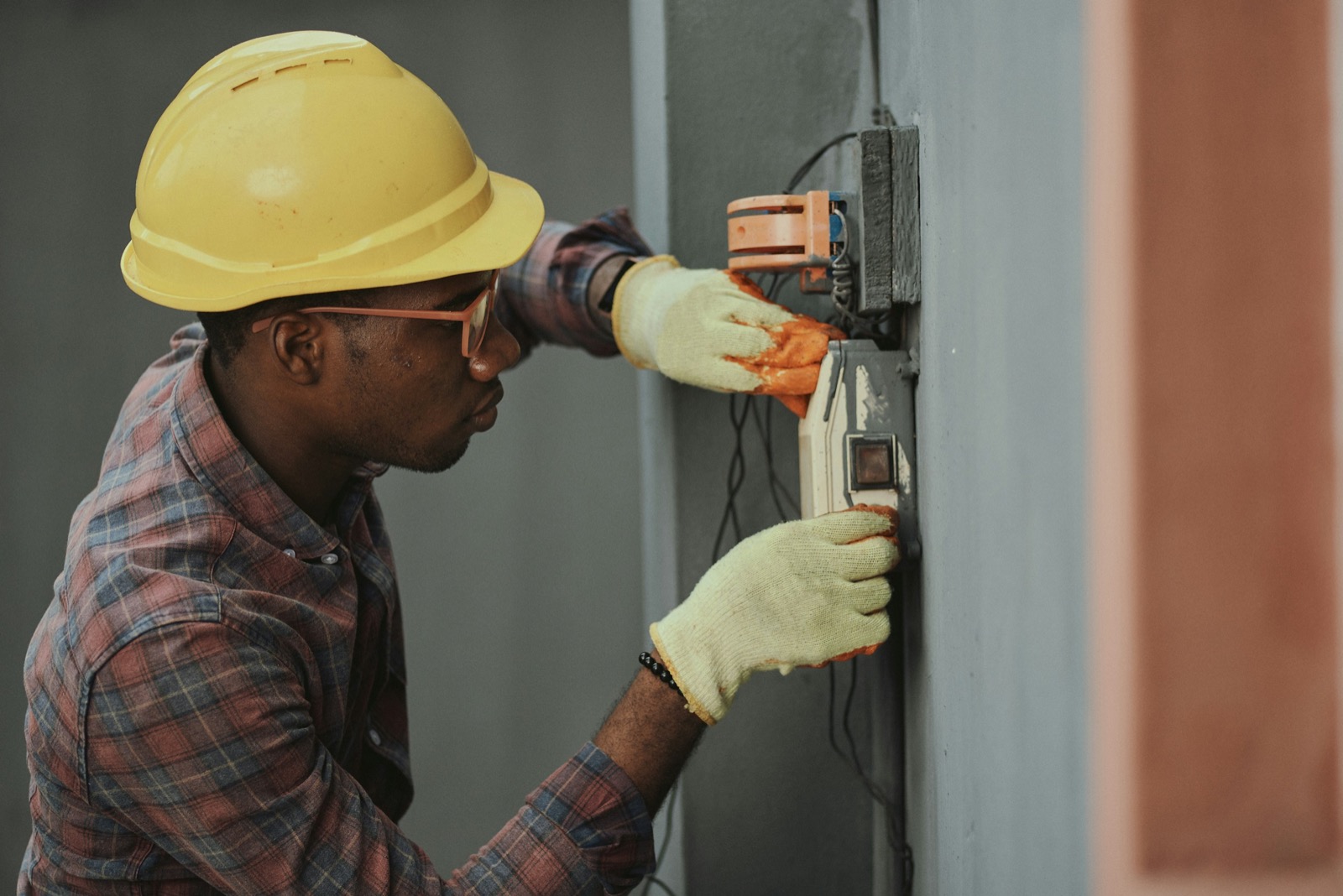 electrician contractor installing wiring wearing yellow hard hat on job site